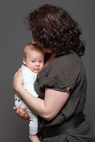 Baby daughter in the arms of mom. Studio shot. — Stock Photo, Image