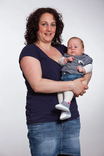 Feliz madre sosteniendo a su bebé en su brazo. Captura de estudio . —  Fotos de Stock