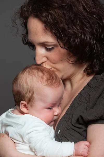 Baby daughter in the arms of mom. Studio shot. — Stock Photo, Image