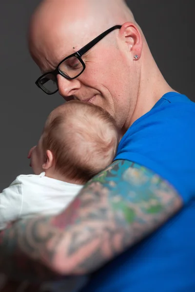 Happy dad with glasses holding his baby. Studio shot. — Stock Photo, Image