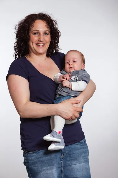 Happy mother holding her baby in her arm. Studio shot. — Stock Photo, Image