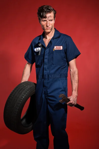 Retro cincuentena mecánico coche masculino que sostiene la herramienta y el neumático. Estudio sh —  Fotos de Stock
