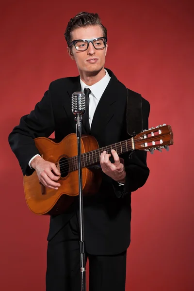 Cantante retro de los años cincuenta con gafas tocando la guitarra acústica. Studi. — Foto de Stock