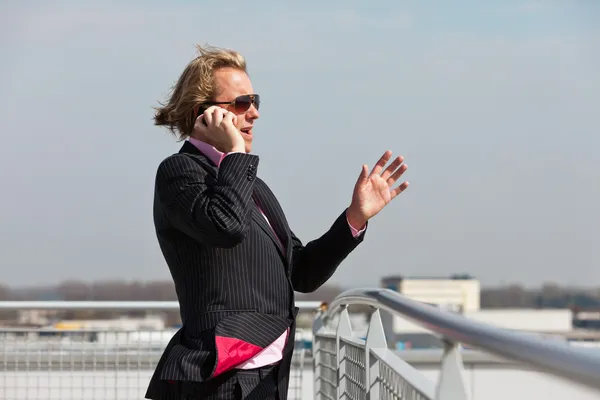 Uomo d'affari con occhiali da sole chiamando con cellulare all'aperto su r — Foto Stock