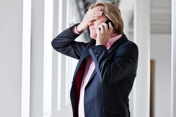 Hombre de negocios serio usando su teléfono celular en la oficina blanca . —  Fotos de Stock