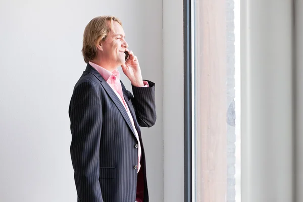 Business man calling with cellphone in front of window office. — Stock Photo, Image