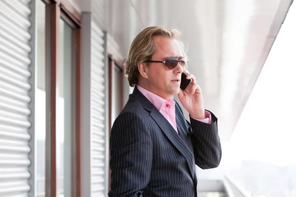 Business man with sunglasses calling with cellphone outdoor on b — Stock Photo, Image