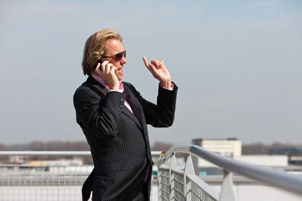 Business man with sunglasses calling with cellphone outdoor on r — Stock Photo, Image