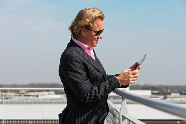 Geschäftsmann mit Sonnenbrille auf dem Dach mit Tablet. — Stockfoto