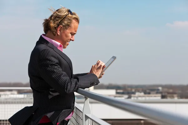 Hombre de negocios con traje azul al aire libre en la azotea usando tableta . —  Fotos de Stock