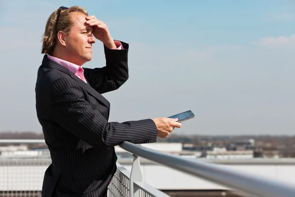 Homem de negócios com terno azul ao ar livre no telhado usando tablet . — Fotografia de Stock