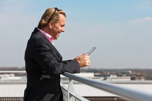 Geschäftsmann mit blauem Anzug draußen auf dem Dach mit Tablet. — Stockfoto