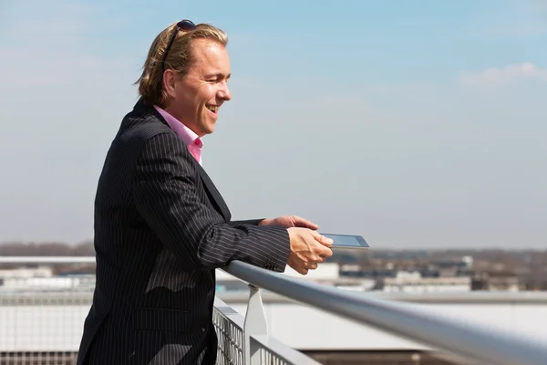 Omul de afaceri cu costum albastru în aer liber pe acoperiș folosind tabletă . — Fotografie, imagine de stoc