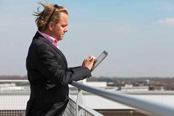 Uomo d'affari con tuta blu all'aperto sul tetto utilizzando tablet . — Foto Stock