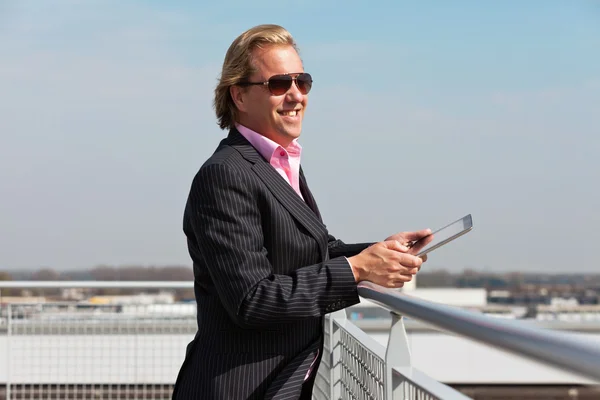 Business man with sunglasses outdoor on rooftop using tablet. — Stock Photo, Image