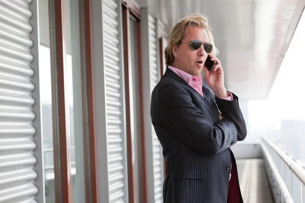 Homme d'affaires avec des lunettes de soleil appelant avec téléphone portable en plein air à o — Photo