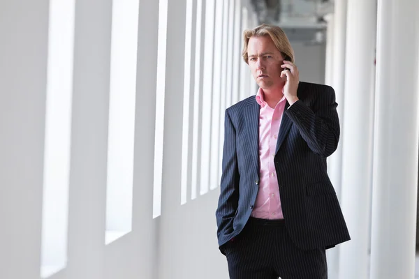 白いオフィスで彼の携帯電話を呼び出すビジネス男. — ストック写真