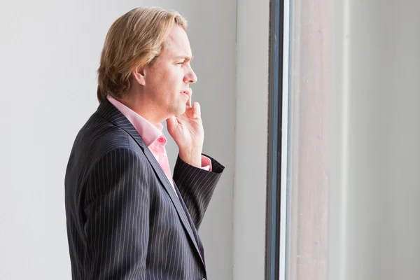 Uomo d'affari che chiama con il cellulare davanti all'ufficio delle finestre . — Foto Stock