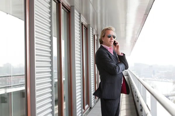 Homme d'affaires avec des lunettes de soleil appelant avec téléphone portable en plein air à o — Photo
