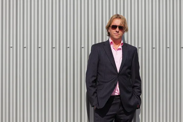 Uomo d'affari con occhiali da sole all'aperto contro parete industriale . — Foto Stock