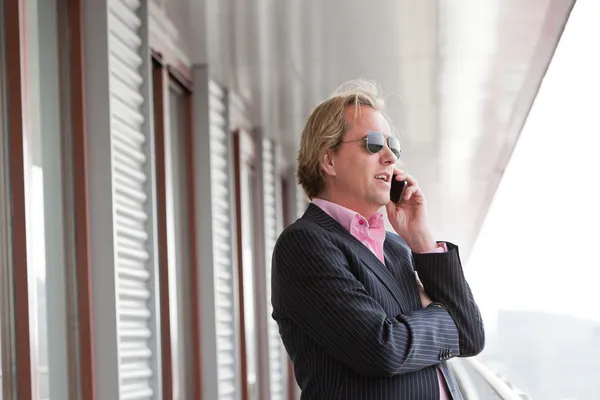 Homme d'affaires avec des lunettes de soleil appelant avec téléphone portable en plein air à o — Photo