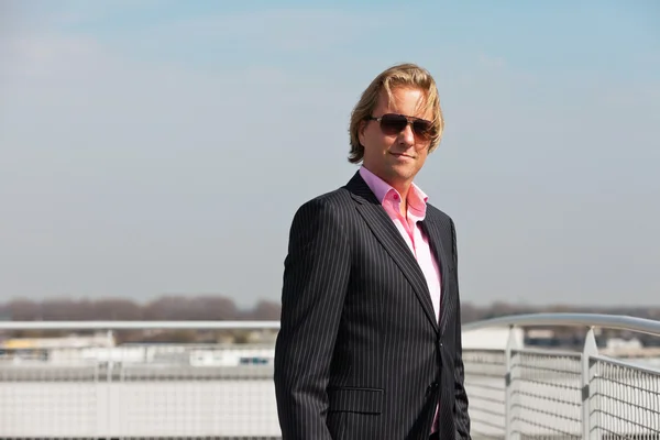 Uomo d'affari con occhiali da sole all'aperto sul tetto di un edificio per uffici — Foto Stock