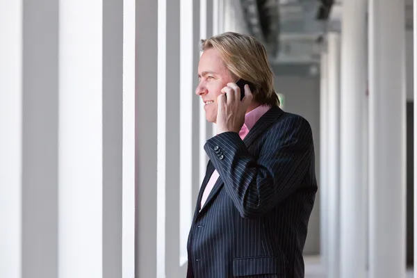 Geschäftsmann telefoniert mit seinem Handy im weißen Büro. — Stockfoto