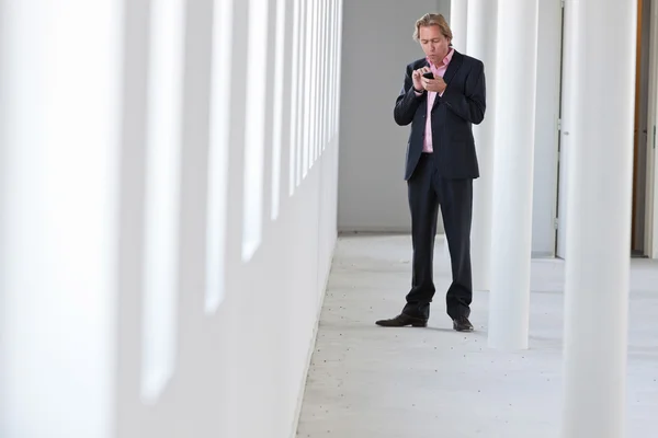 Homme d'affaires appelant avec son téléphone portable dans le bureau blanc . — Photo