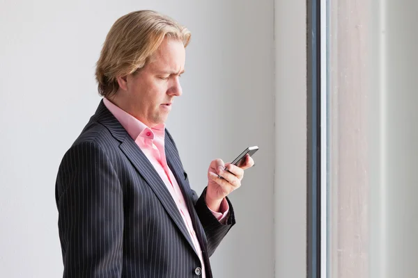 Obchodní muž volání s mobil před okno úřadu. — Stock fotografie