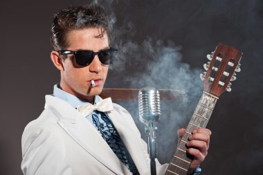 Retro rock and roll singer wearing white suit and black sunglass clipart
