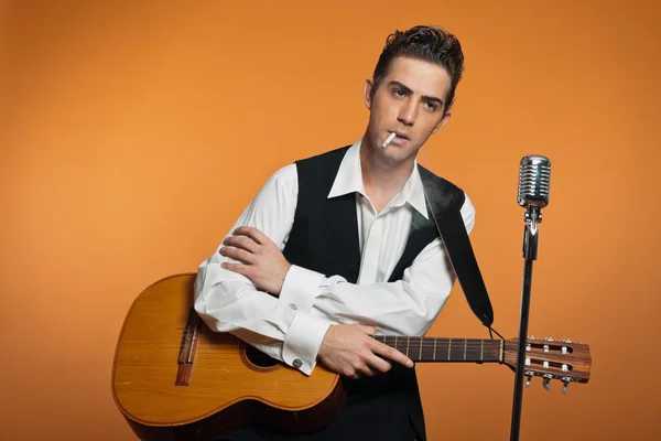Cantante country retro con guitarra vestida de traje negro. Fumar cigarro — Foto de Stock