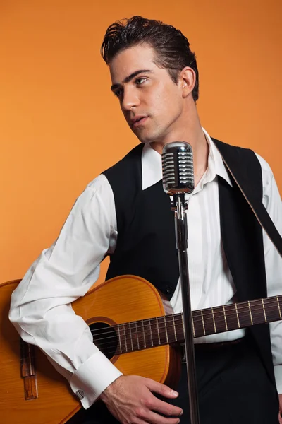 Retro country singer with guitar wearing black suit. Studio shot — Stock Photo, Image