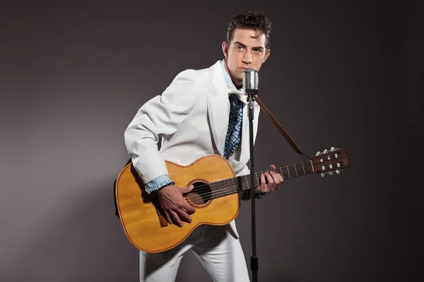 Retro rock and roll singer with guitar wearing white suit. Studi — Stock Photo, Image