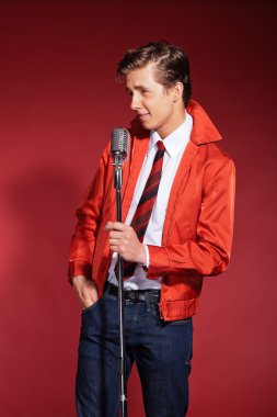 retro ellili şarkıcı kırmızı ceket kot pantolon ve kravat takıyor. Vint