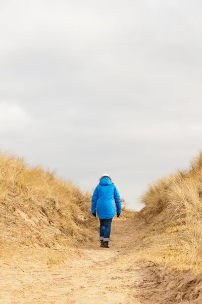 Promenade touristique sur le sentier dans un paysage de dunes herbeuses avec ciel nuageux — Photo