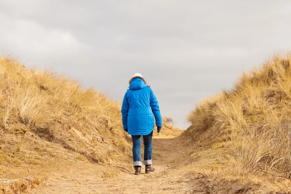 Promenade touristique sur le sentier dans un paysage de dunes herbeuses avec ciel nuageux — Photo