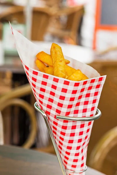 French fries in red and white blocked paper bag on table outdoor — Stock Photo, Image