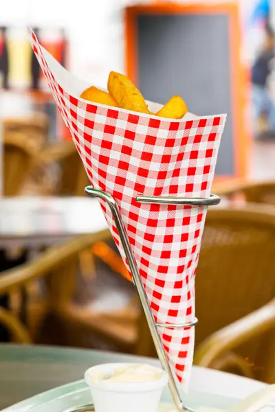 French fries in red and white blocked paper bag on table outdoor — Stock Photo, Image