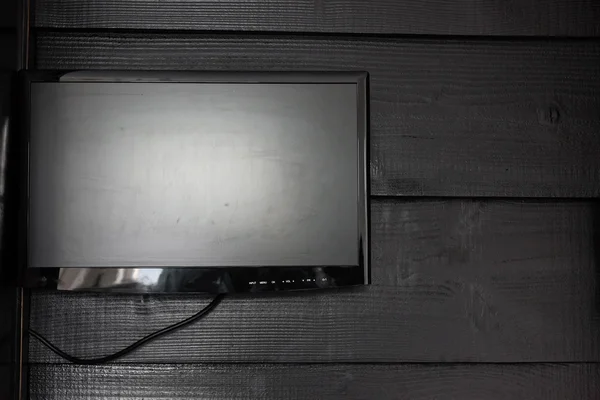 Schwarzer Flachbildfernseher an schwarzer Holzwand. — Stockfoto