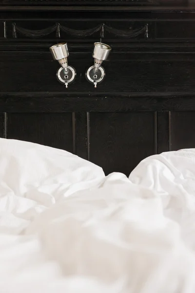 Close-up bed lichten op zwart hout. hotelkamer. — Stockfoto