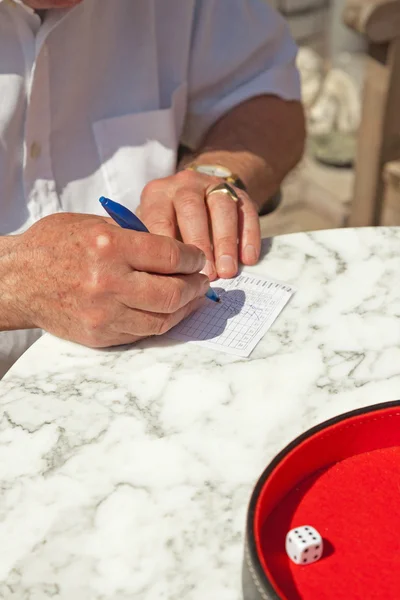 Старший чоловік пише свій рахунок на папері на відкритому повітрі в саду. Відтворення — стокове фото