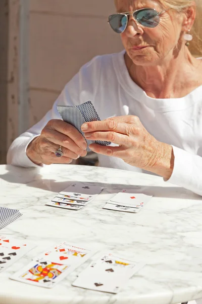Старша жінка грає в карткову гру на відкритому повітрі в саду . — стокове фото