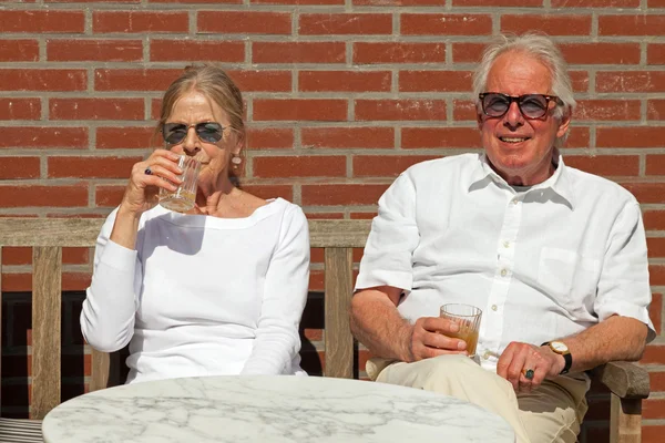 Gelukkige senior paar zitten buiten in de tuin genieten van fruit ju — Stockfoto