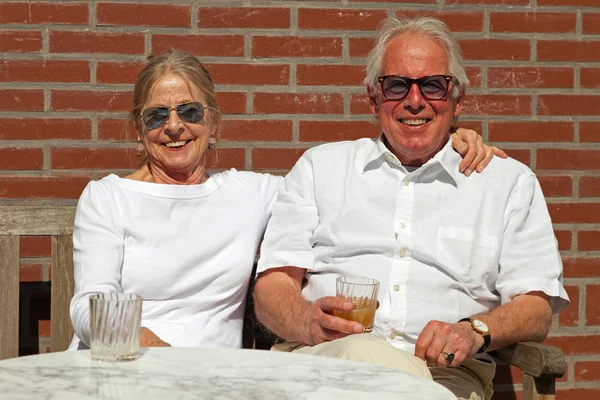 Happy senior couple sitting outdoors in garden enjoying fruit ju — Stock Photo, Image