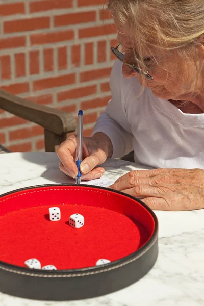 Senior woman writing his score on paper outdoor in garden. Playi — Stock Photo, Image