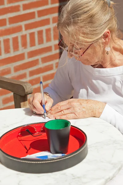 Donna anziana scrivere la sua partitura su carta all'aperto in giardino. Playi — Foto Stock