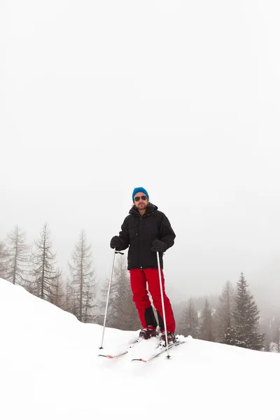 Homem de esqui feliz com chapéu azul em pé na neve . — Fotografia de Stock