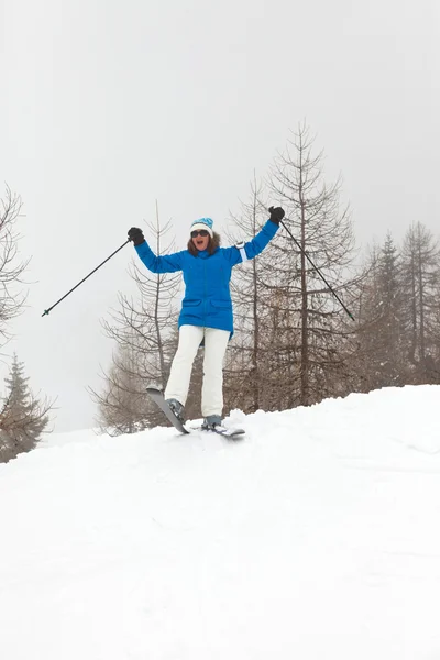 Счастливая лыжница, стоящая в снегу с соснами . — стоковое фото