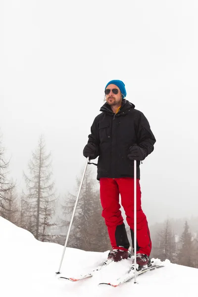Счастливый лыжник в синей шляпе, стоящий в снегу . — стоковое фото