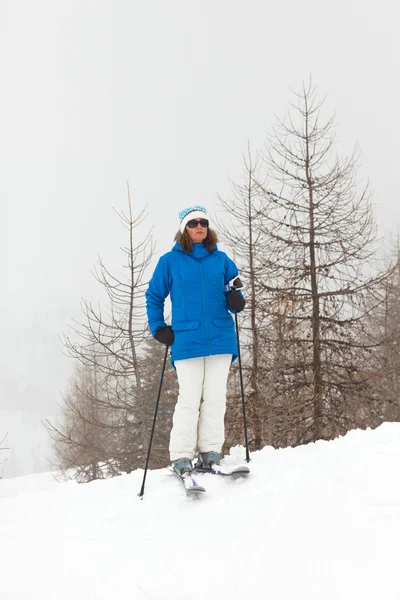 松の木に雪の中で立って幸せスキー女性. — ストック写真